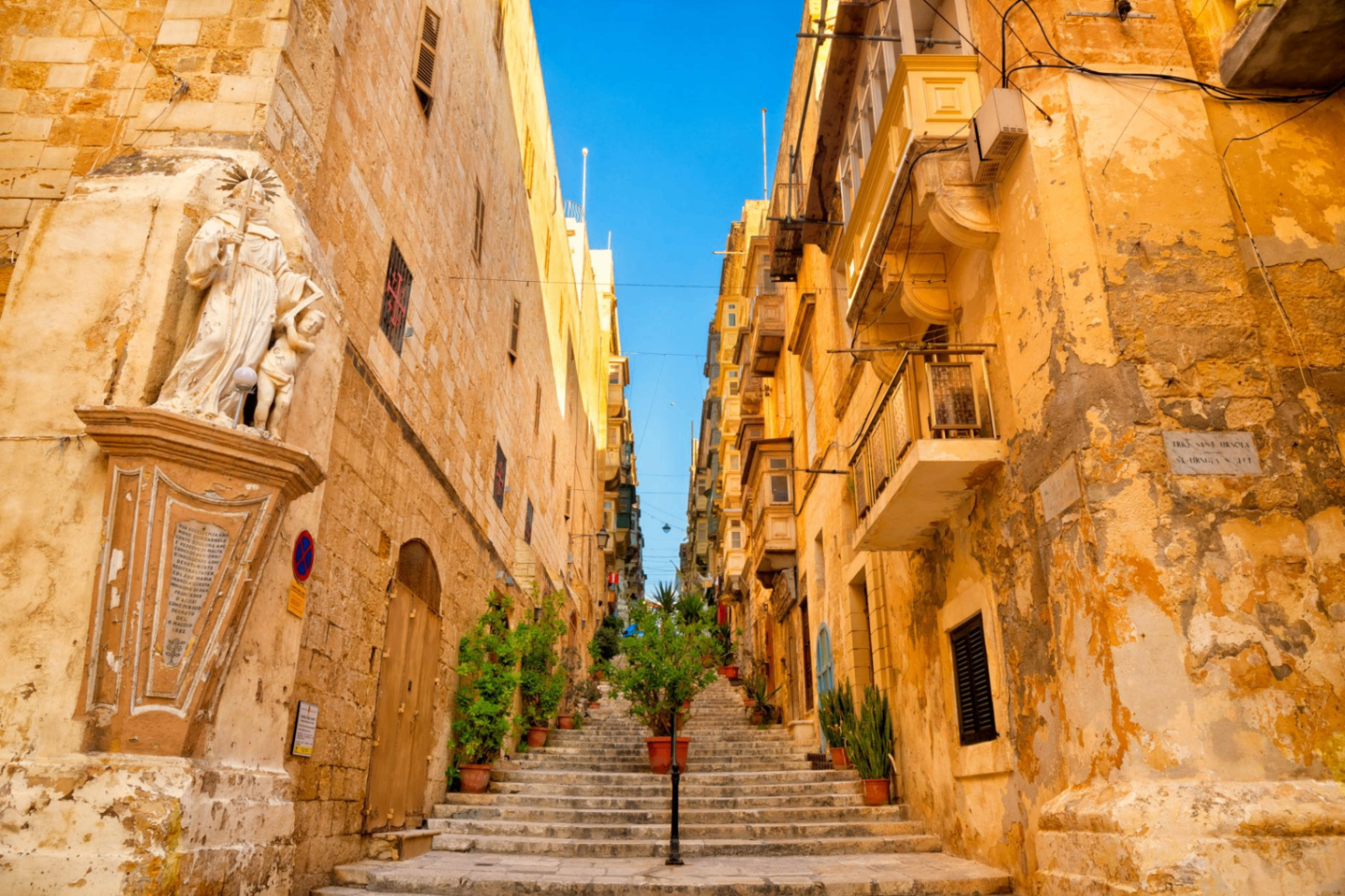 Sunlit limestone staircase in a historic Valletta street